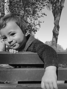 Black and whit portrait of a 10 month old baby leaning over park bench