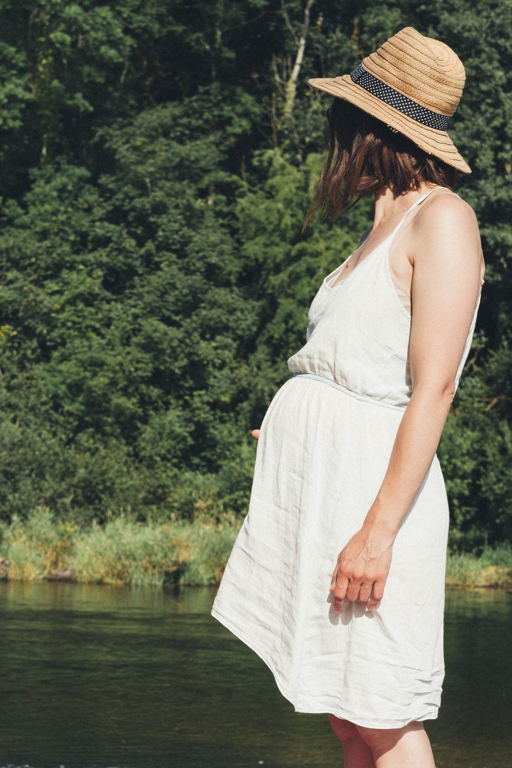 Pregnant woman stands by a river